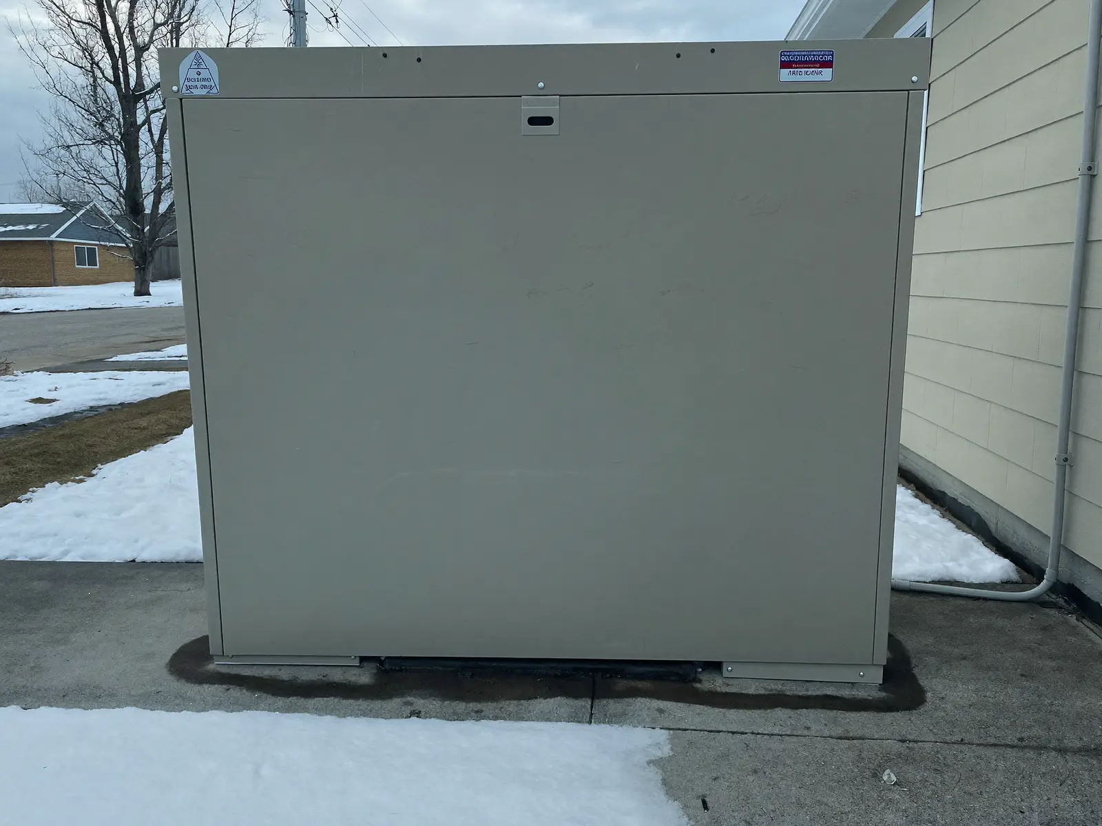 Standby home generator installed beside a house in winter