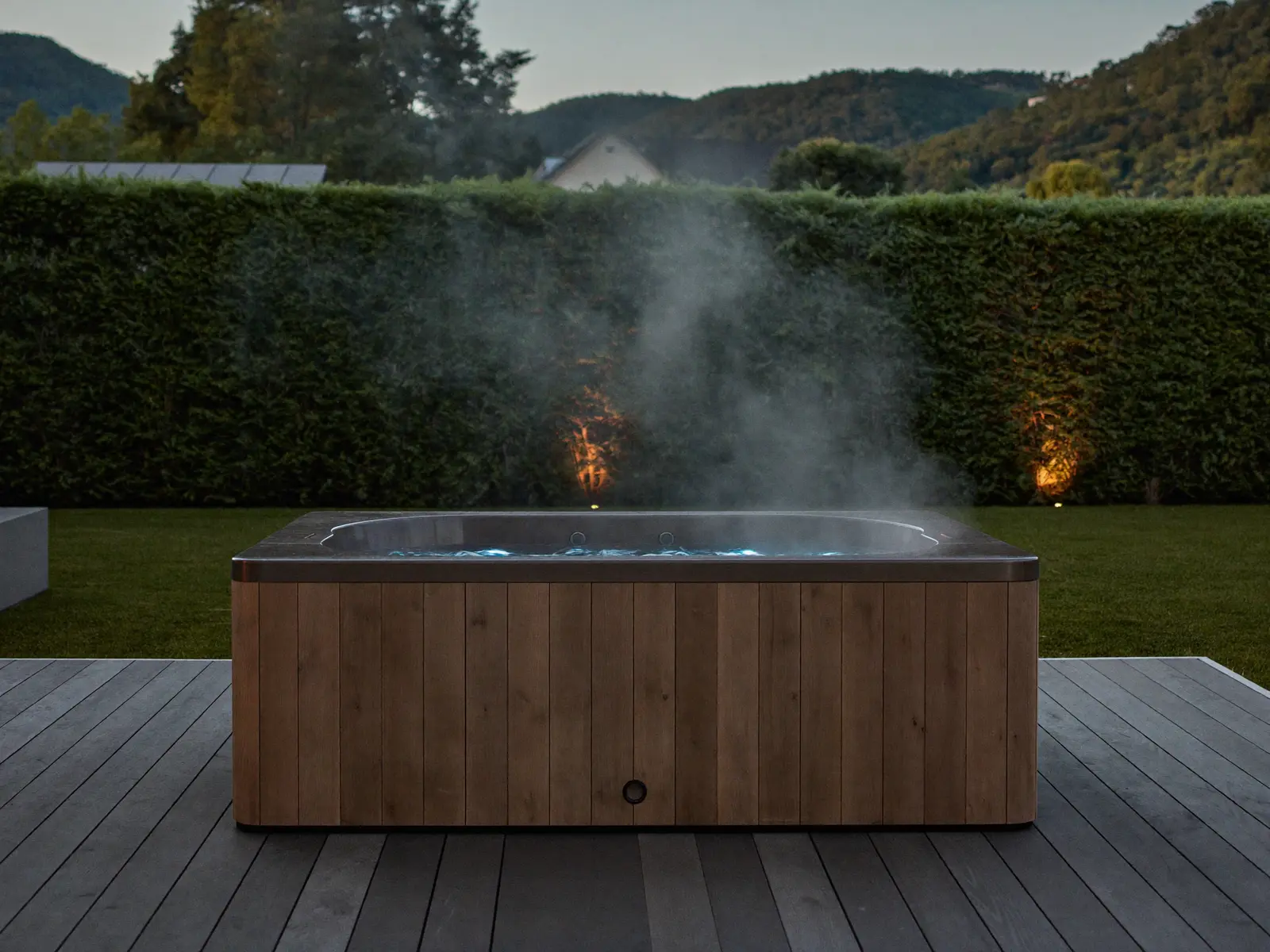 Backyard hot tub with underwater lighting at dusk